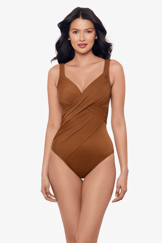 Woman wearing a bronze brown one-piece swimsuit with a wrap style on the bust