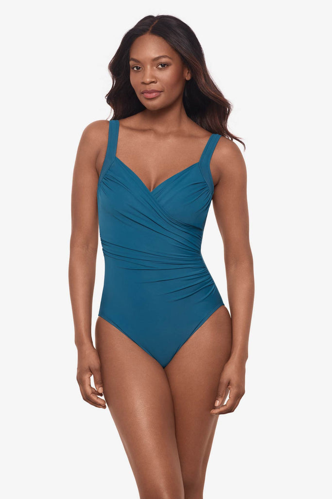 Woman wearing an aegean blue one-piece swimsuit with wrap detail