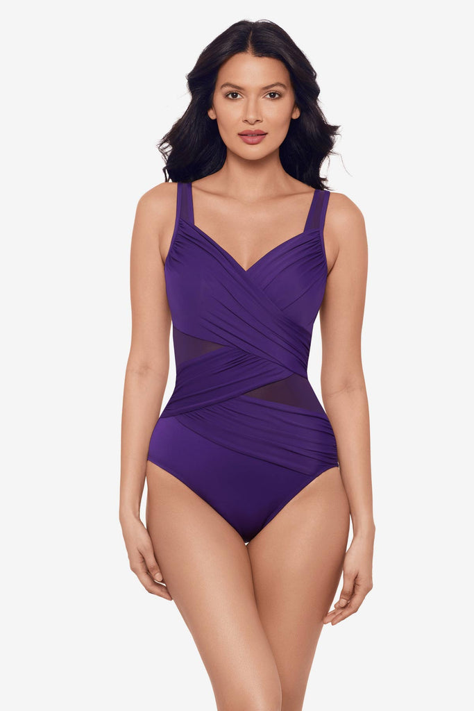 Woman wearing a mulberry purple one-piece swimsuit with mesh cut outs on each side