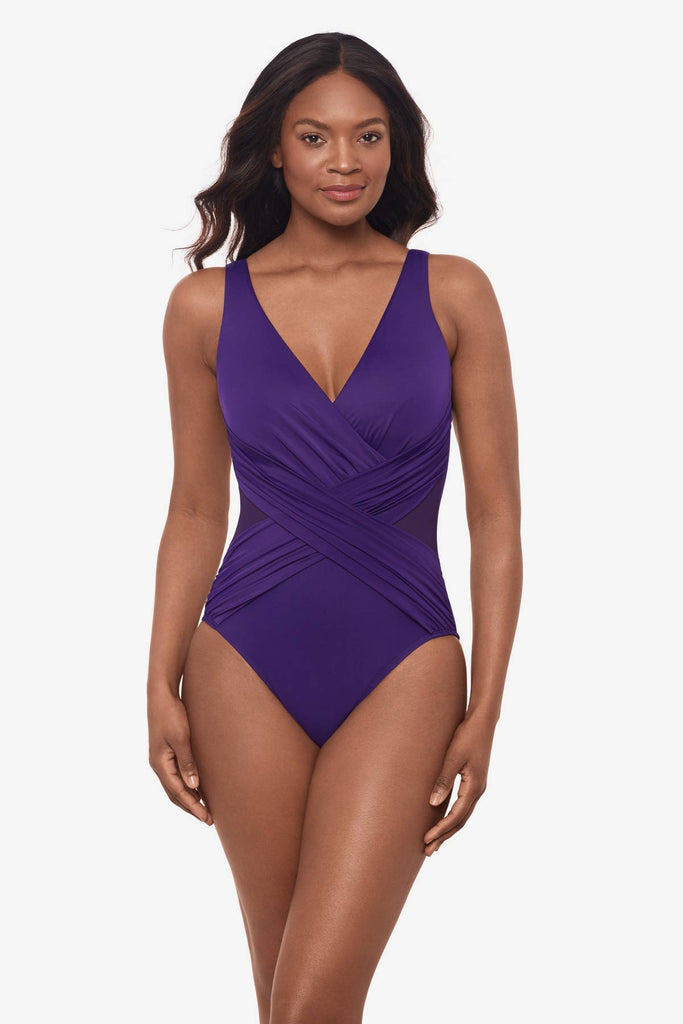 Woman wearing a mulberry purple one-piece swimsuit with mesh cut outs on each side