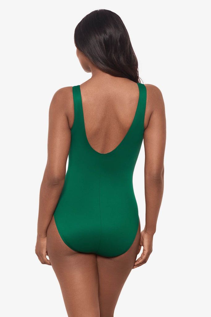 Woman faced away wearing a malachite green one-piece swimsuit with a high neckline