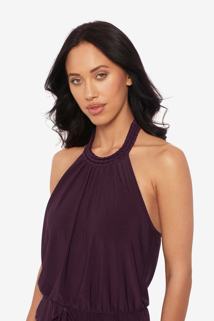 Close up of woman wearing a prune purple swim romper with a high neckline