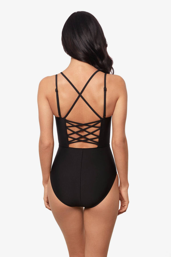 Woman facing away wearing a black one-piece swimsuit with detailed straps