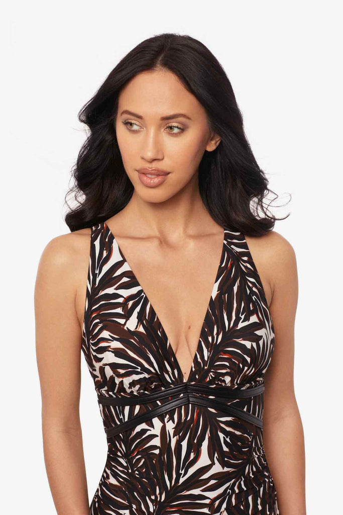 Close up of woman wearing a multicolor one-piece swimsuit with a palm leaf print