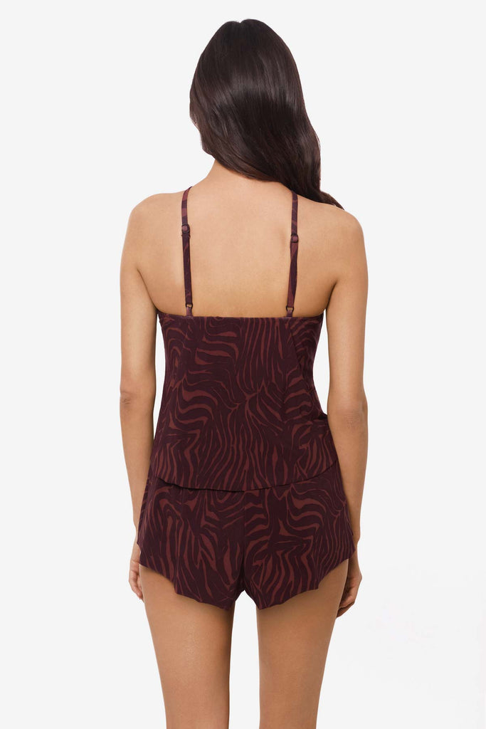 Woman faced away wearing a multicolor swim romper with and abstract animal print