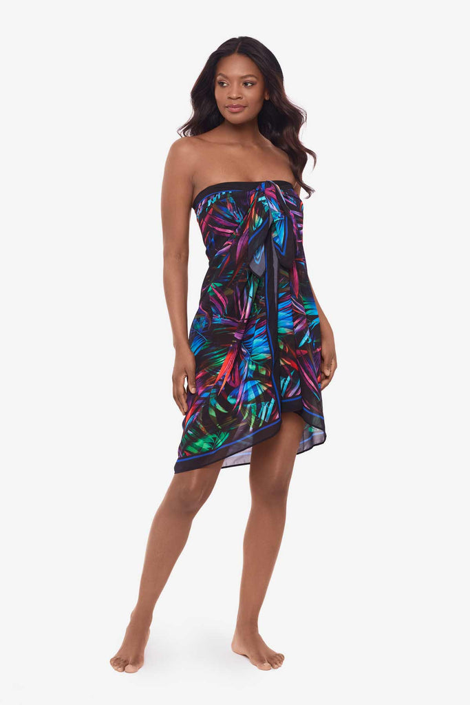 Woman wearing a cover up tied at the bust with a bright neon palm leaf pattern