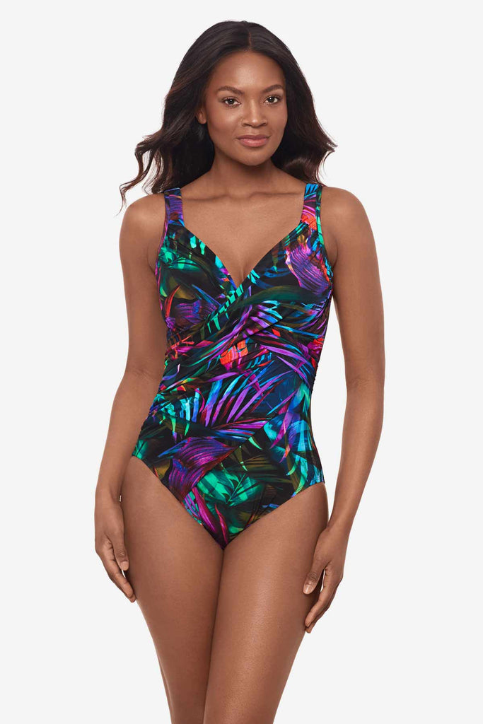 Woman wearing a multicolor one-piece swimsuit with bright neon palm leaves