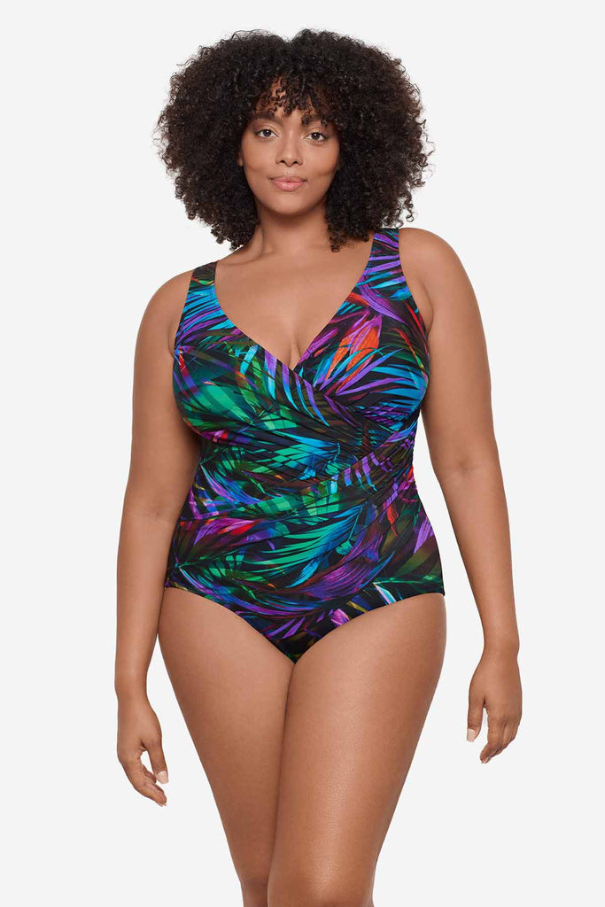 Woman wearing a multicolor one-piece swimsuit with neon palm leaves