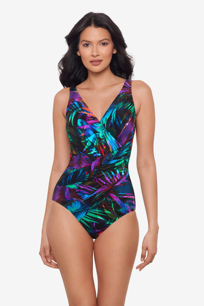 Woman wearing a multicolor one-piece swimsuit with neon palm leaves