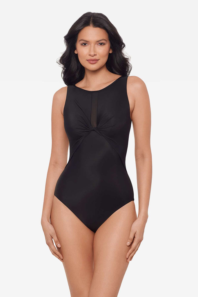 Woman wearing an all-black one-piece swimsuit with cinching at the breasts