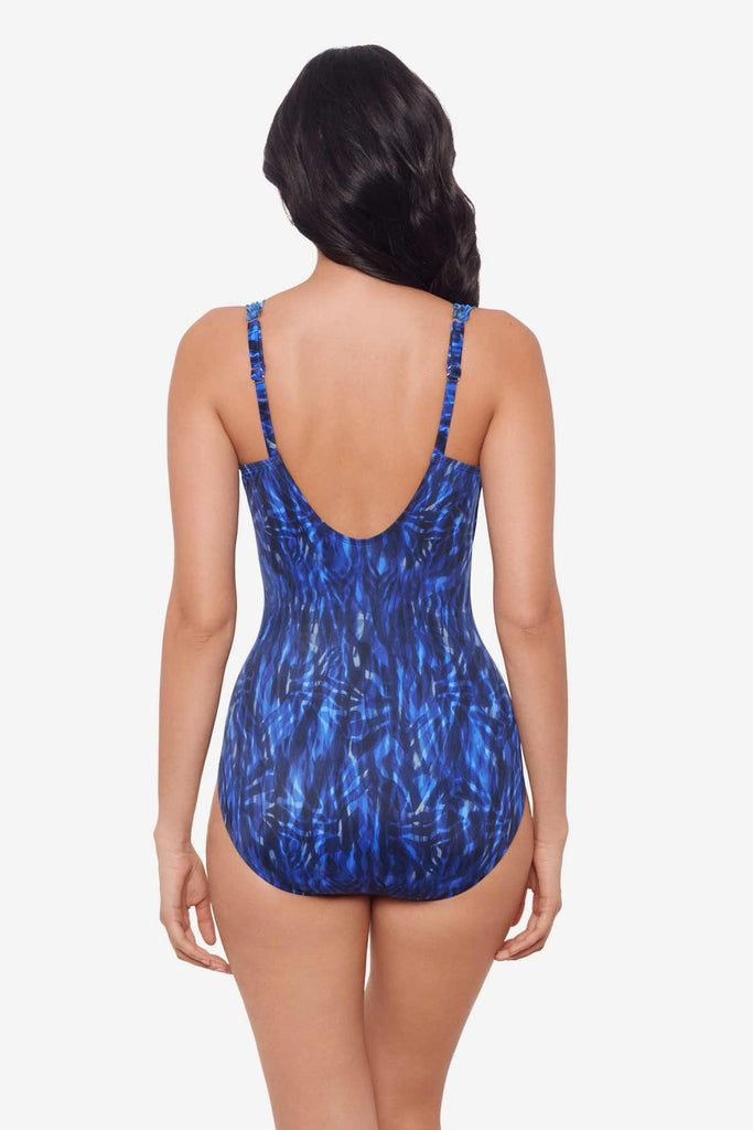 Woman turned away wearing a black and blue one-piece swimsuit with details on the straps