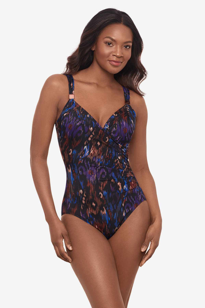 Woman facing right wearing a multicolored one-piece swimsuit with strap details