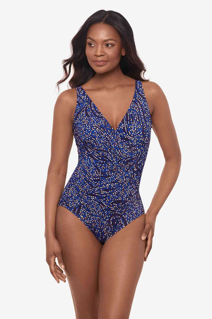 Woman looking left wearing a one-piece multicolor swimsuit with abstract dots