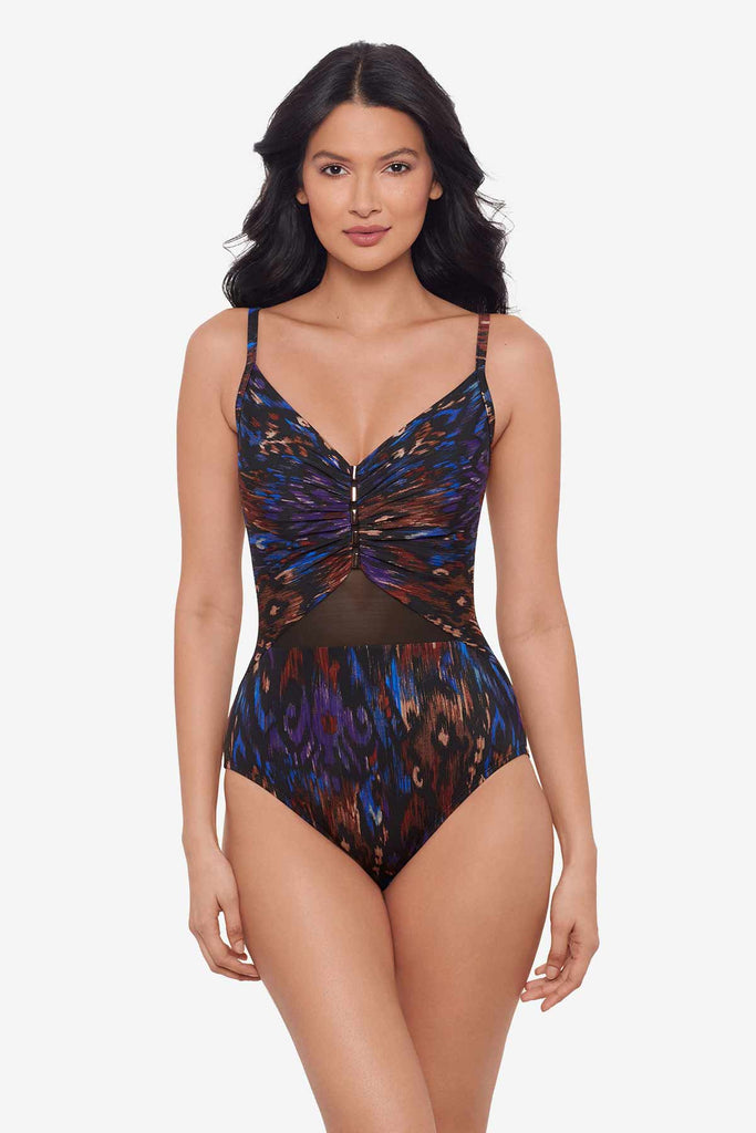 Woman wearing a multi-colored one piece swimsuit with mesh on sternum