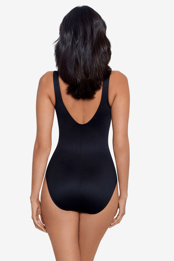 Woman facing away wearing a black one-piece swimsuit with a high neckline