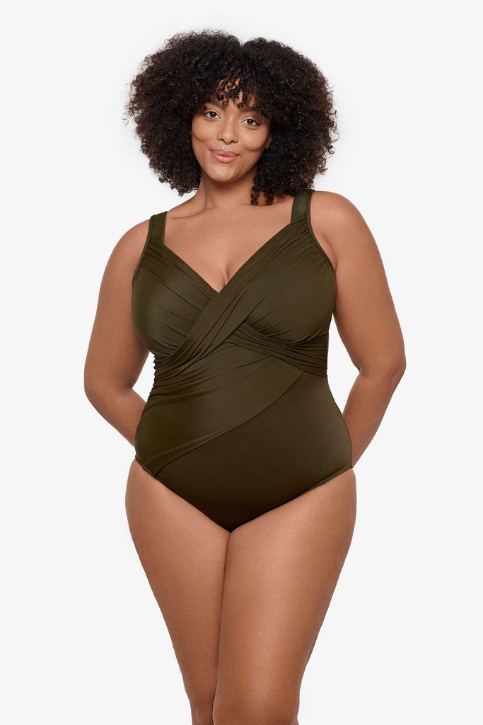 Woman wearing a nori green one-piece swimsuit with wrap detail on the front