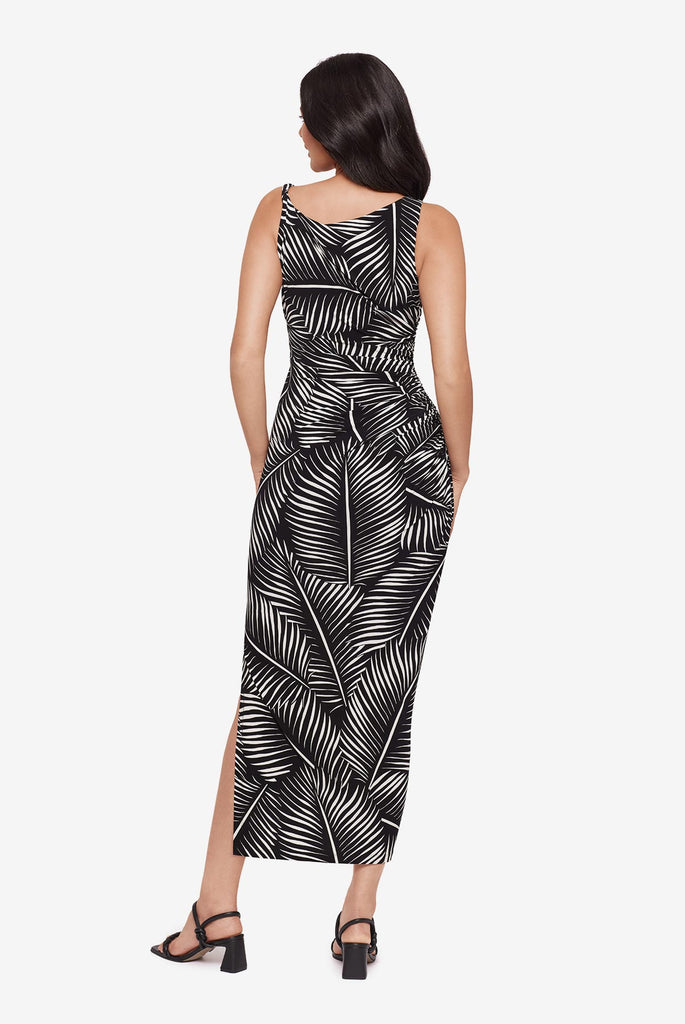 Woman turned away wearing a black and white dress with a palm leaf print