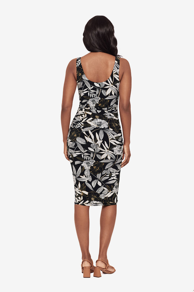 Woman turned away wearing a black multicolored leaf printed dress