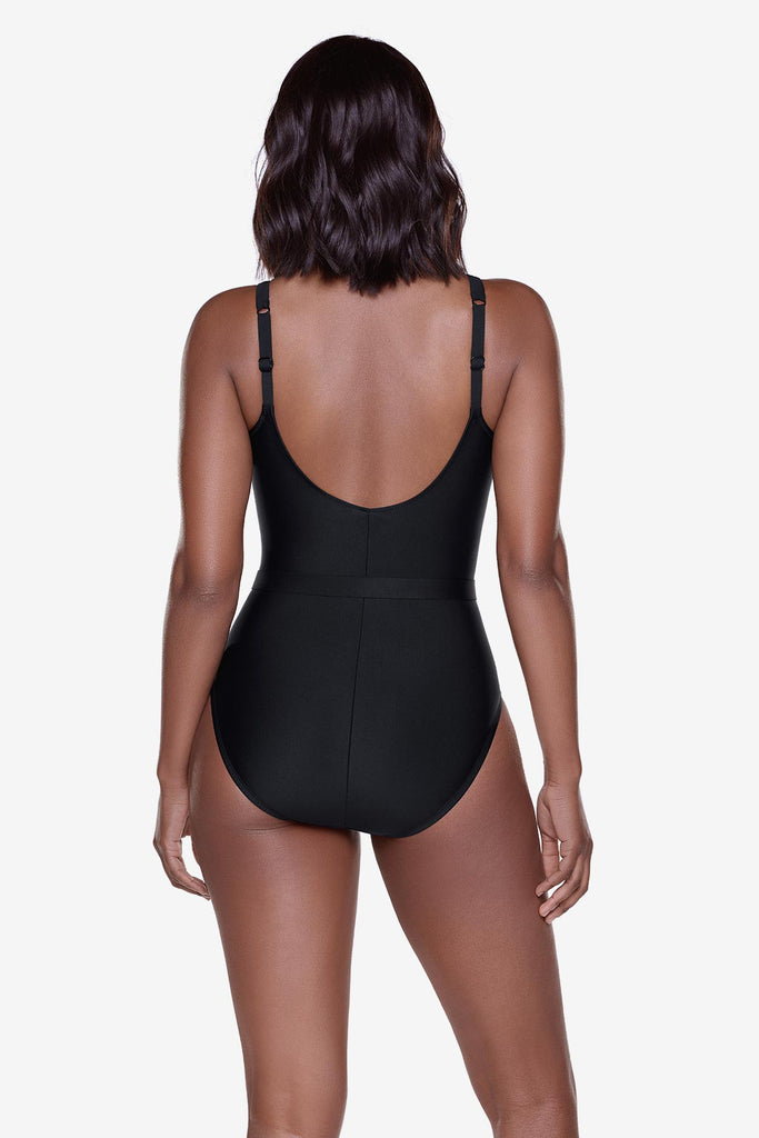 Woman turned away wearing a black one-piece swimsuit with belt detail