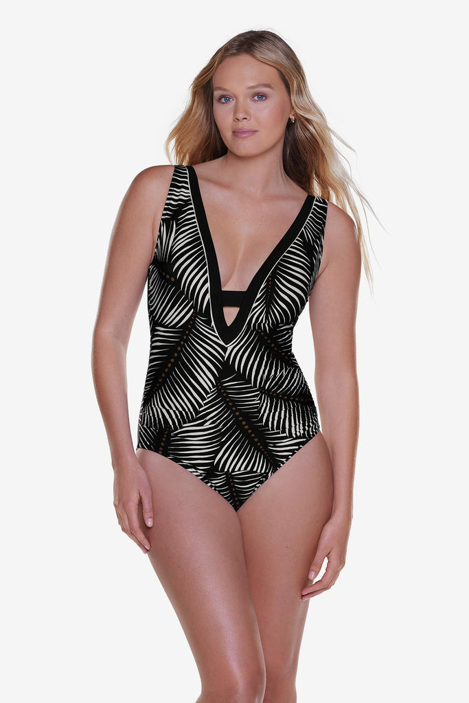 Woman wearing a deep v-neckline one-piece swimsuit with a black and white palm leaf print