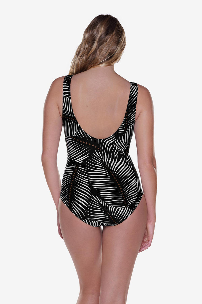 Woman turned away wearing a one-piece swimsuit with a black and white palm leaf print