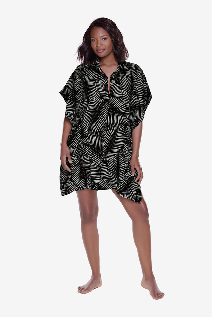 Woman wearing an oversized swim shirt cover up with a black and white leaf print