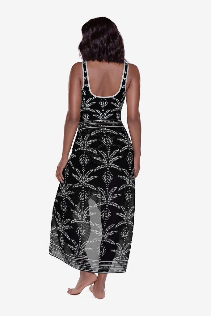 Woman turned away wearing a black and white print swim cover up around her waist