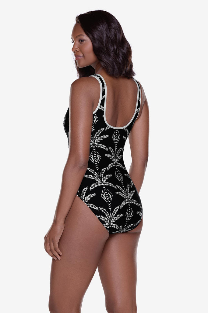 Woman turned left wearing a black and white printed one-piece swimsuit with white piping