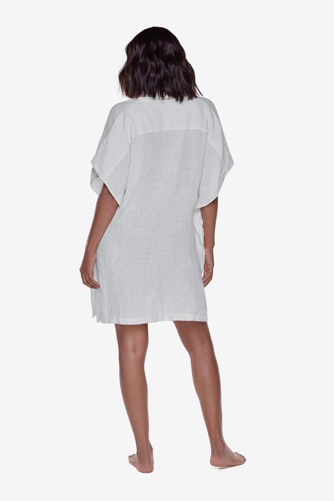 Woman turned away wearing an ivory-colored oversized beach shirt