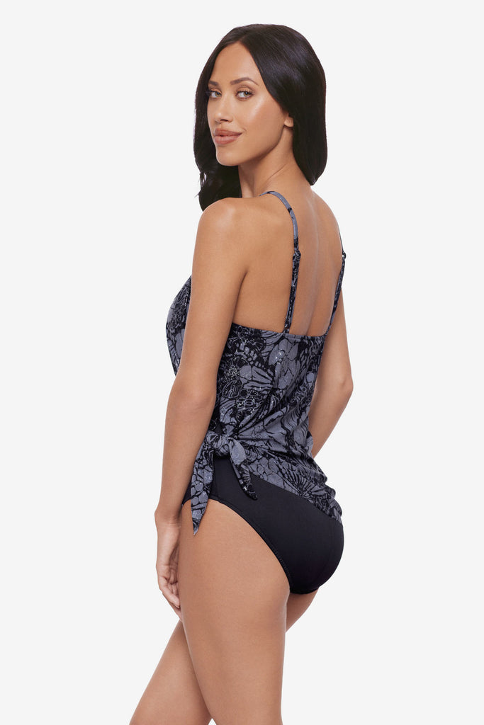 Woman turned left wearing a shimmery blue and black floral tankini top