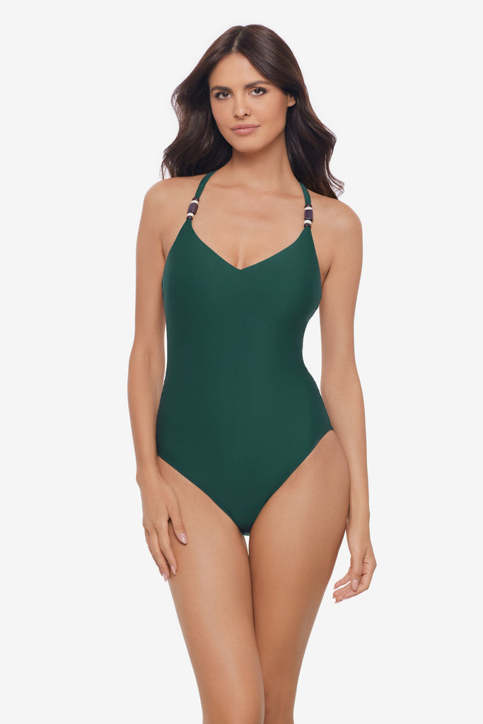 Woman wearing a dark green one-piece swimsuit with beads on the straps