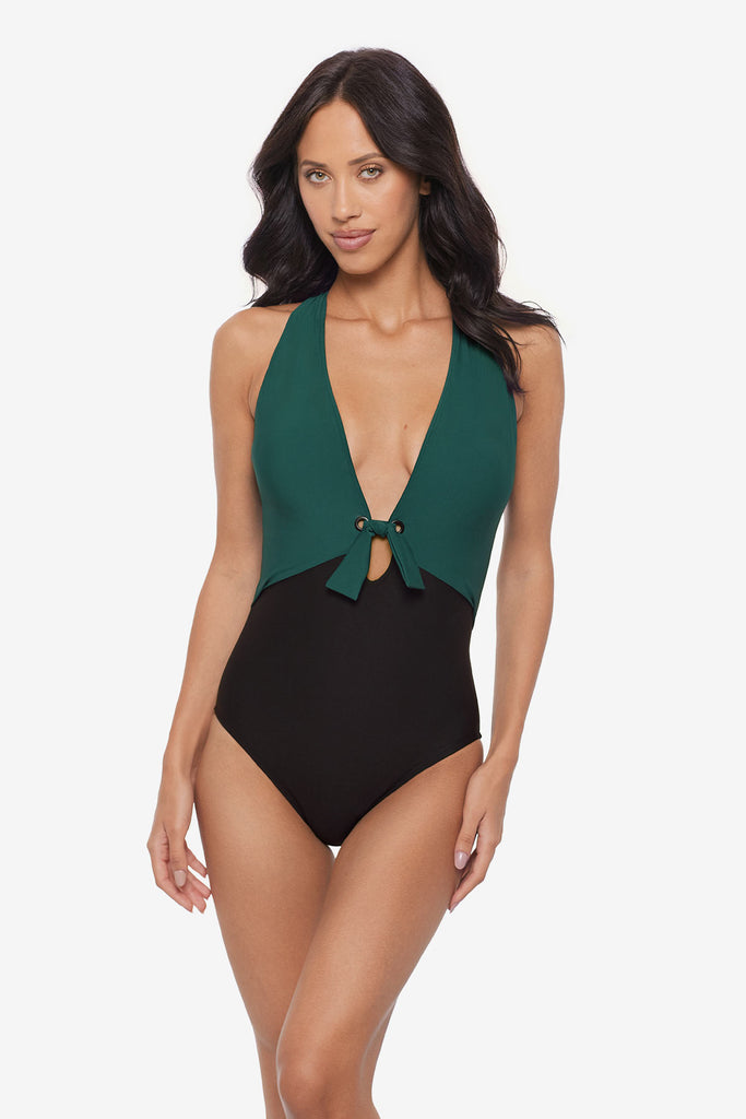 Woman wearing a green and black one-piece swimsuit with a deep V neck